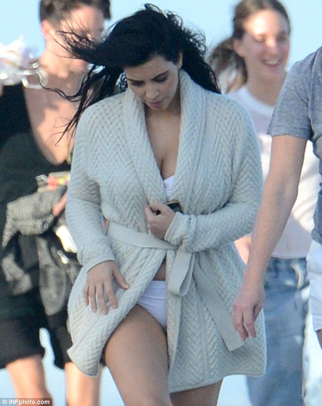 Kim Kardashian covers her bump with a loose cardigan as she makes her way to bikini